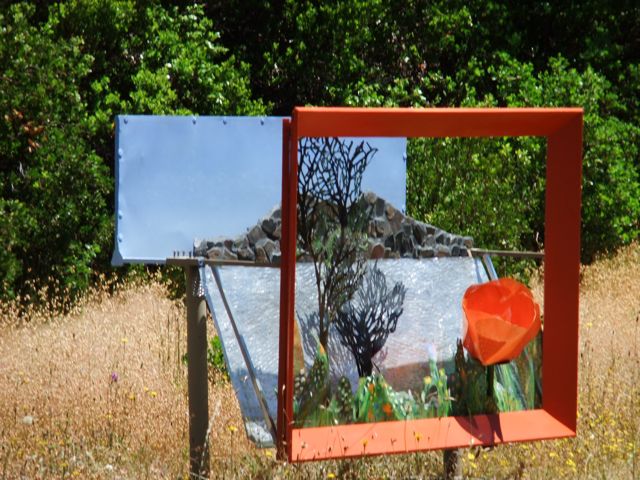 Steel Diarama by Alicia Lee Farnsworth  layers painted perfornated metal and mixed media to create a bueautiful lakeside scene with a big california poppy in the foreground